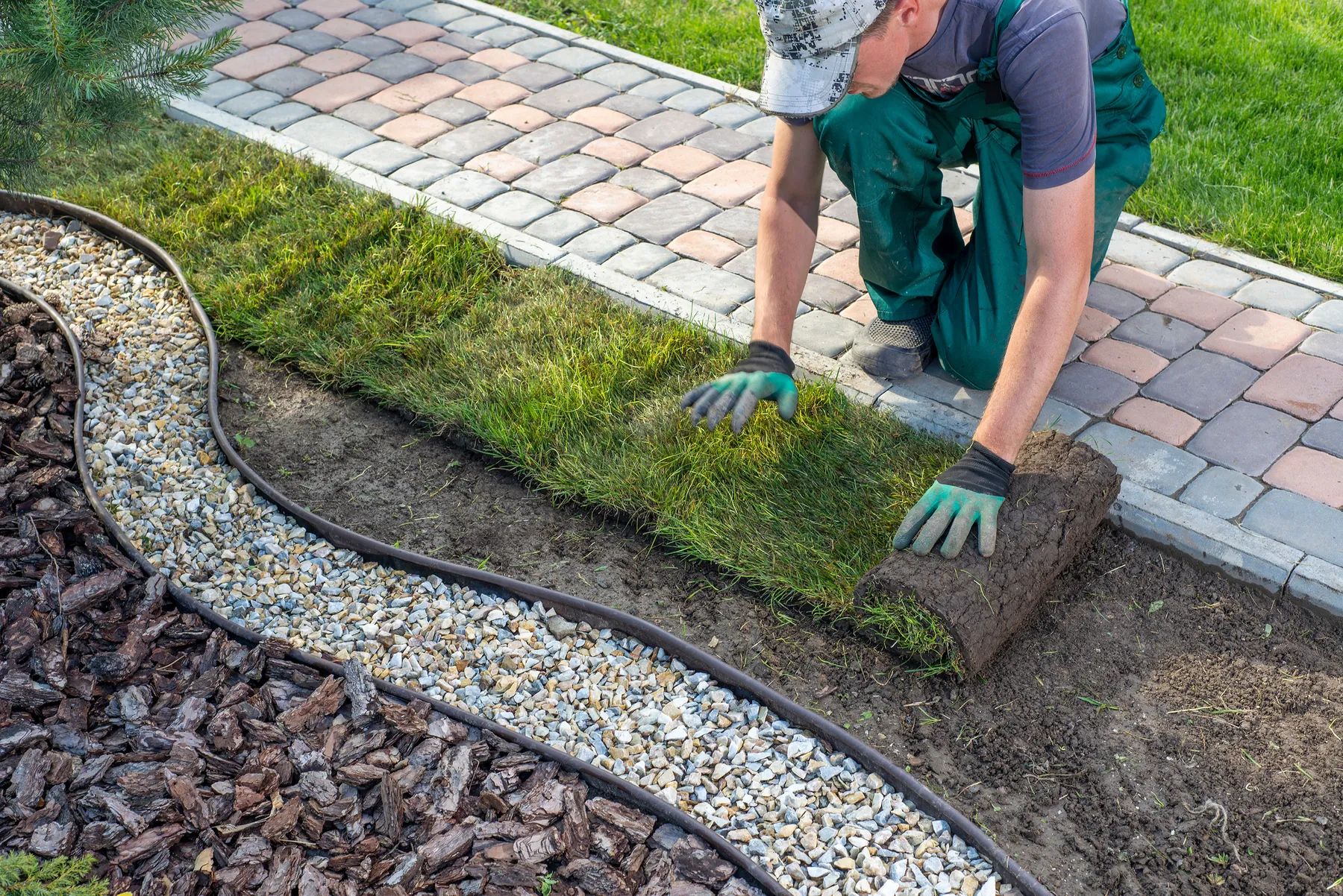 New sod, gravel edging and pavers being installed beside a walkway