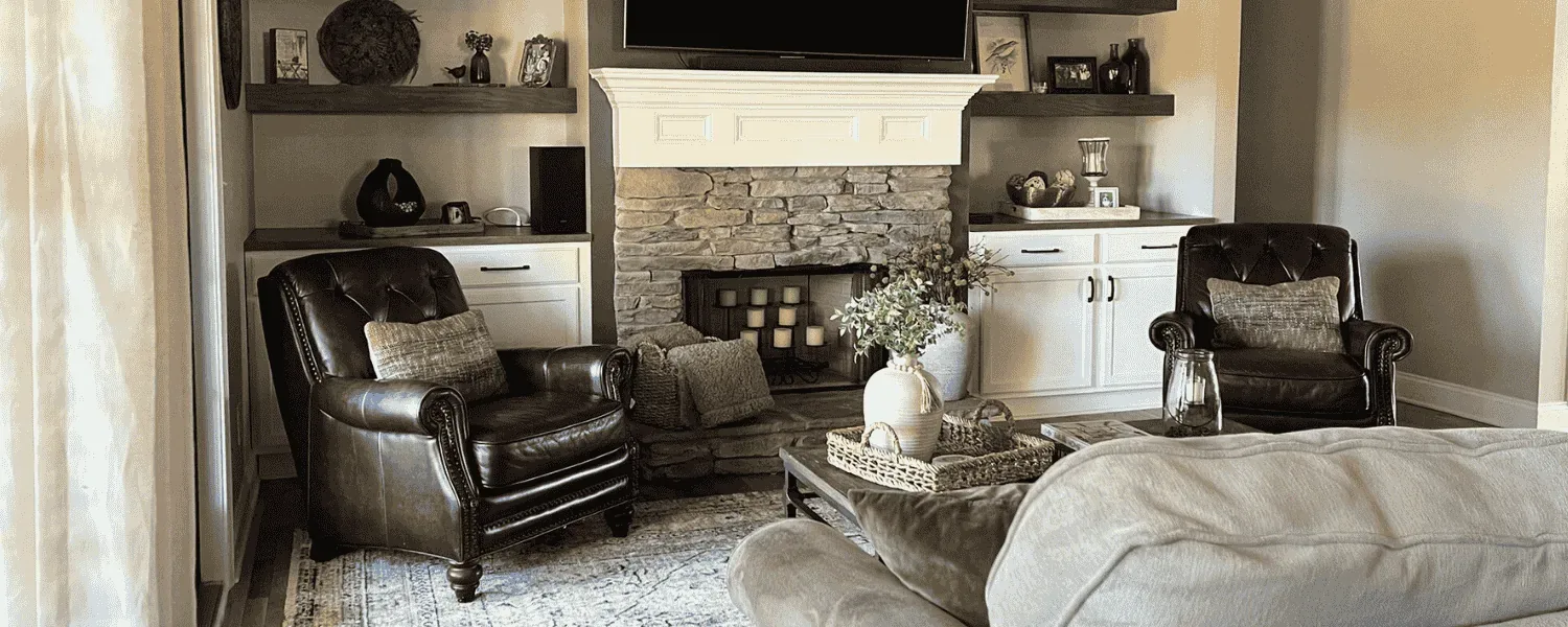 Living room with a white stone fireplace, leather armchairs and layered shelf styling
