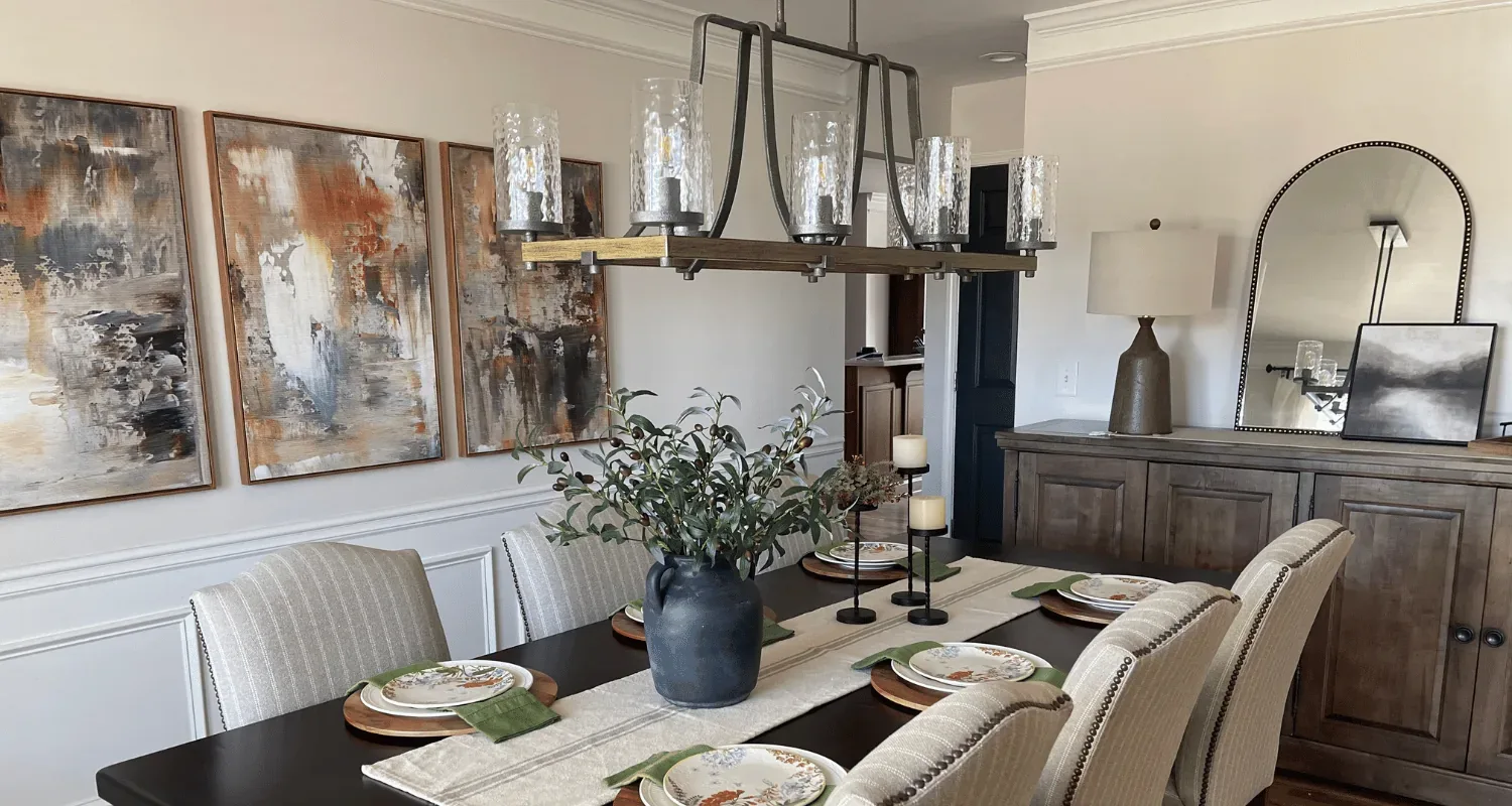 Formal dining room designed by Modern Comfort Interiors with a linen runner, olive branch centerpiece and iron chandelier