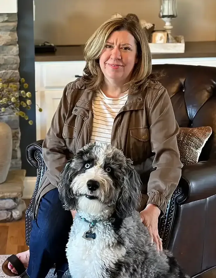 Holly Dempsey seated with her dog Milo in a living room she designed