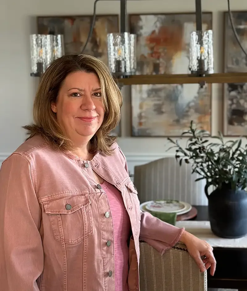 Holly Dempsey, principal designer of Modern Comfort Interiors, standing in a styled dining room
