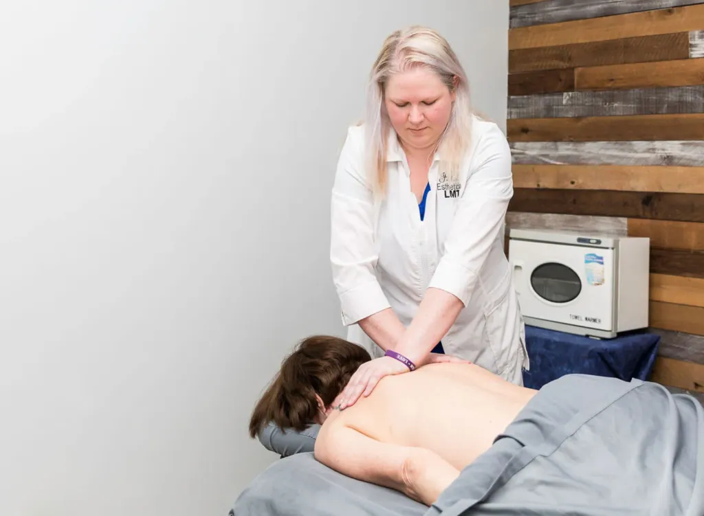 Therapist leaning into a client's back with both hands during a deep tissue massage in Hoschton, GA