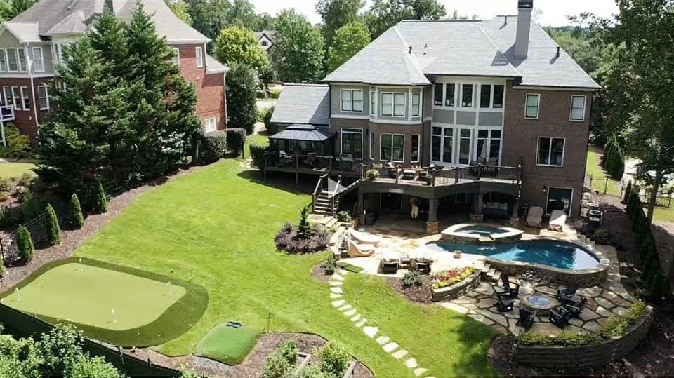 Finished backyard with a swimming pool, raised spa, deck, stone patio, lawn, and putting green
