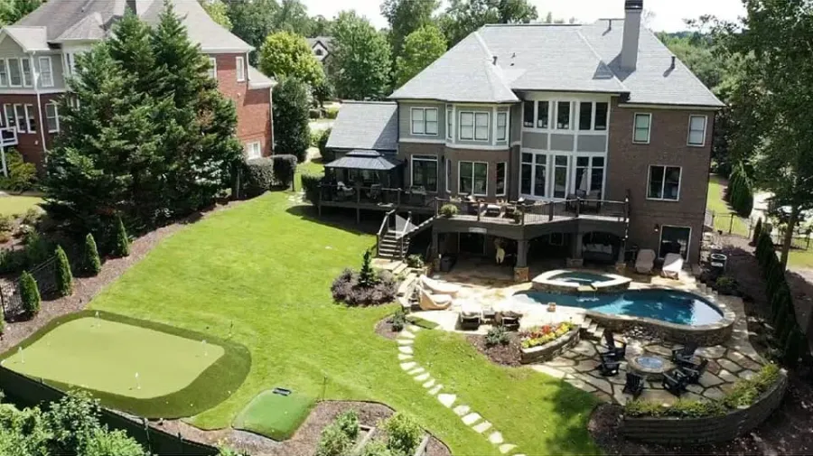 Finished backyard with a swimming pool, raised spa, deck, stone patio, lawn, and putting green