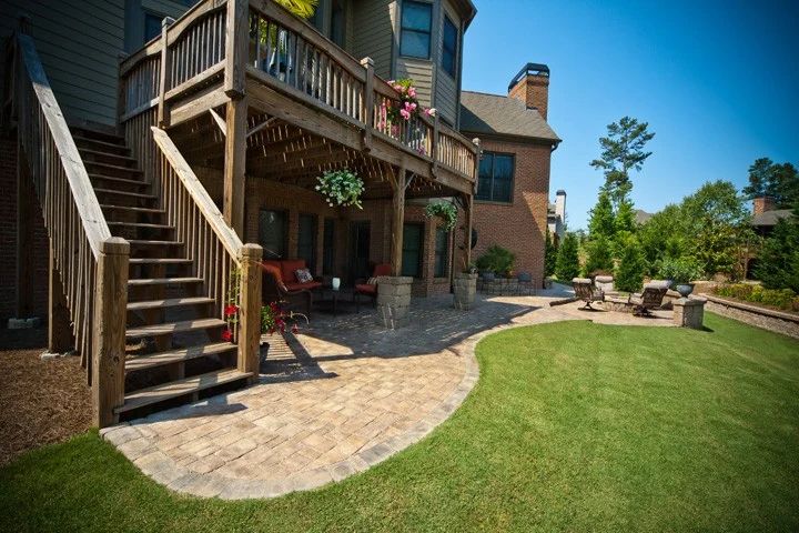 Covered deck above a stone patio with outdoor seating and lawn