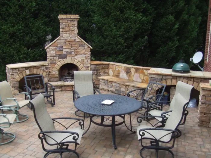 Stone outdoor kitchen with built-in grill, fireplace, and dining table