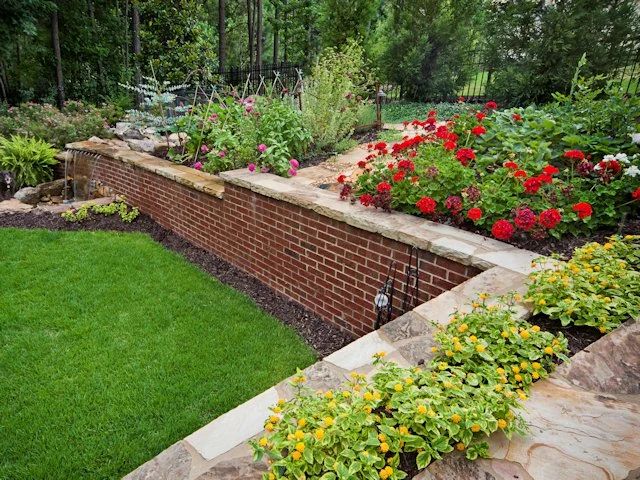 Brick retaining wall supporting a planted garden beside a lawn