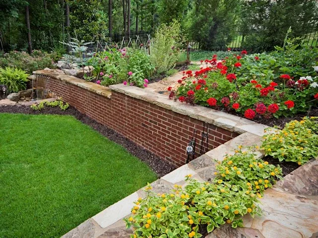 Brick retaining wall supporting a planted garden beside a lawn
