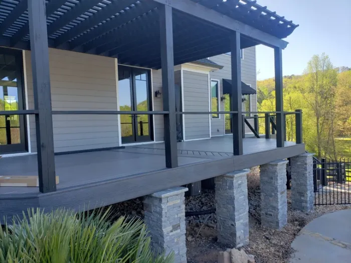 Composite deck and pergola with black rails and stone columns