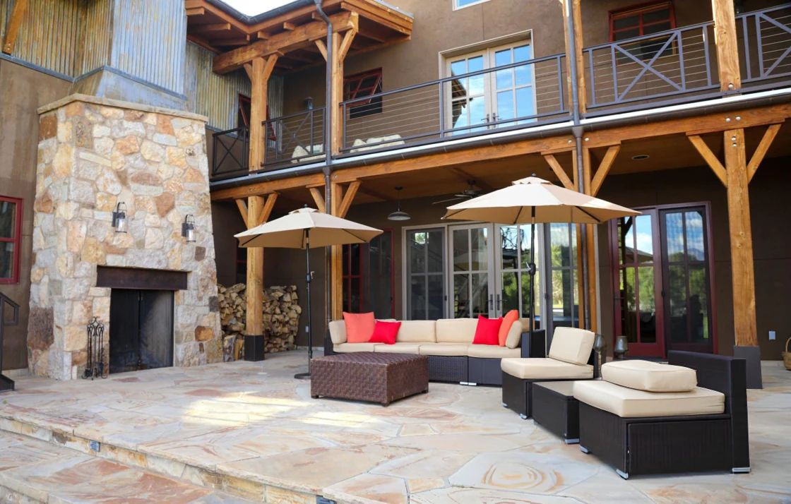 Furnished stone patio and outdoor fireplace beneath a large wood deck