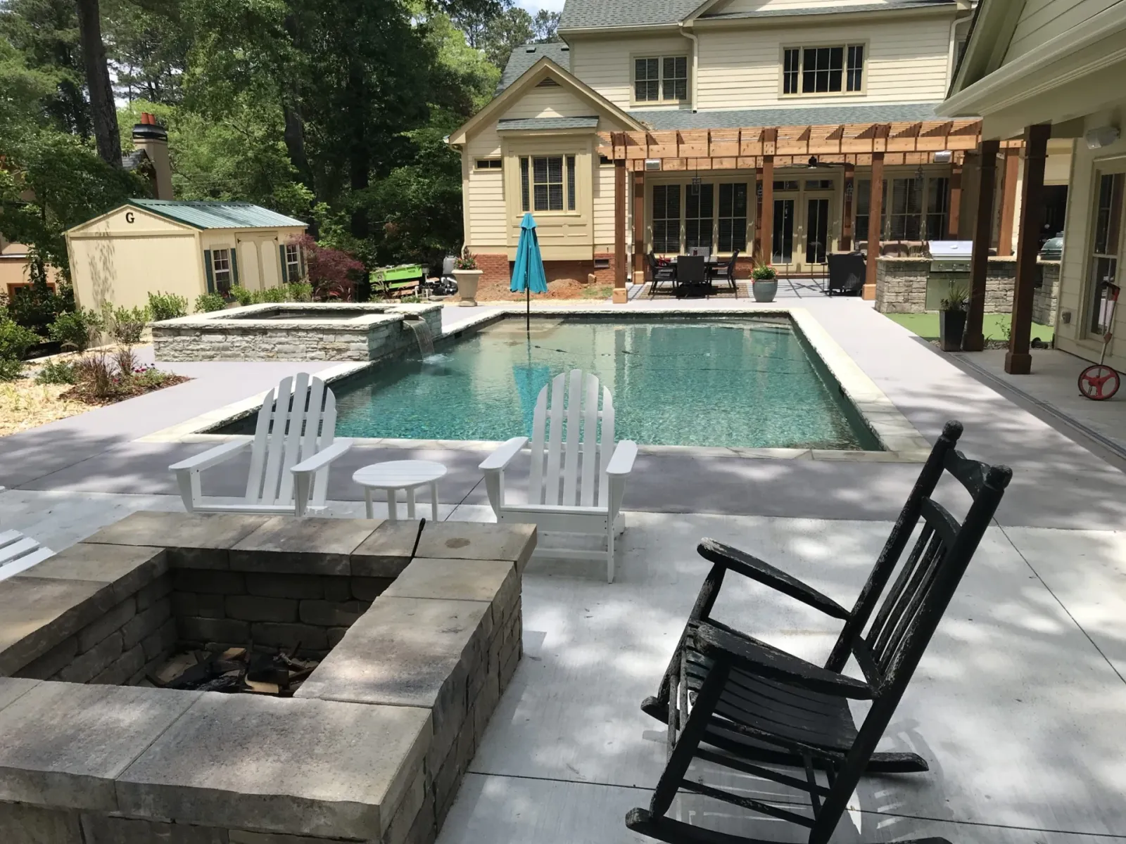 Swimming pool and stone fire pit with a pergola and outdoor seating