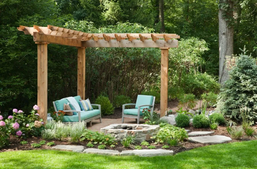 Garden seating beneath a timber pergola beside a stone fire pit