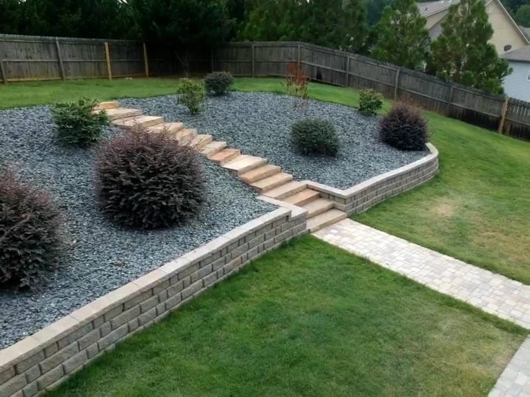 Tiered retaining walls and central stairs framing planted garden beds