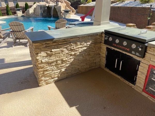 Poolside stone outdoor kitchen with dining furniture
