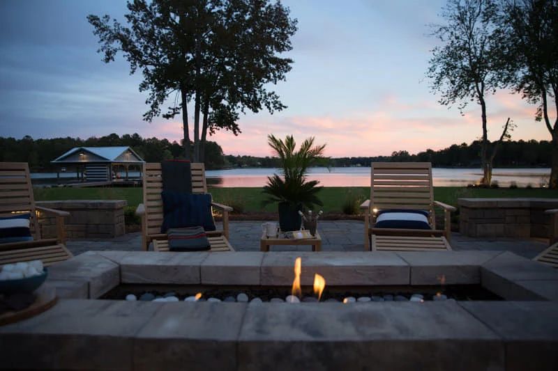 Stone fire pit and outdoor seating overlooking the lake at sunset