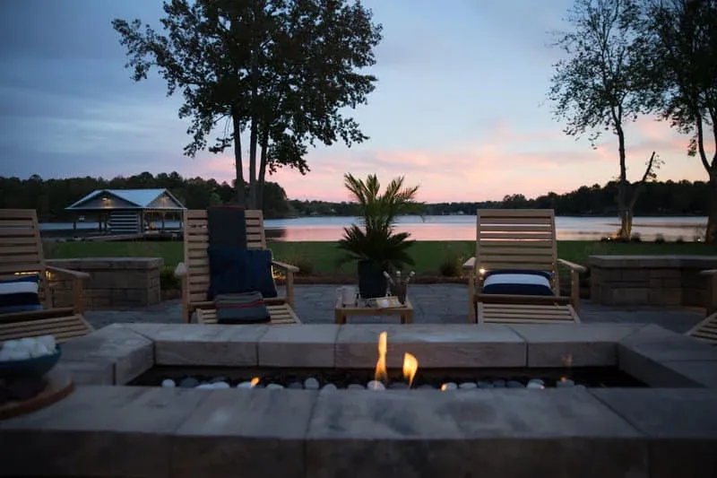 Stone fire pit and outdoor seating overlooking the lake at sunset