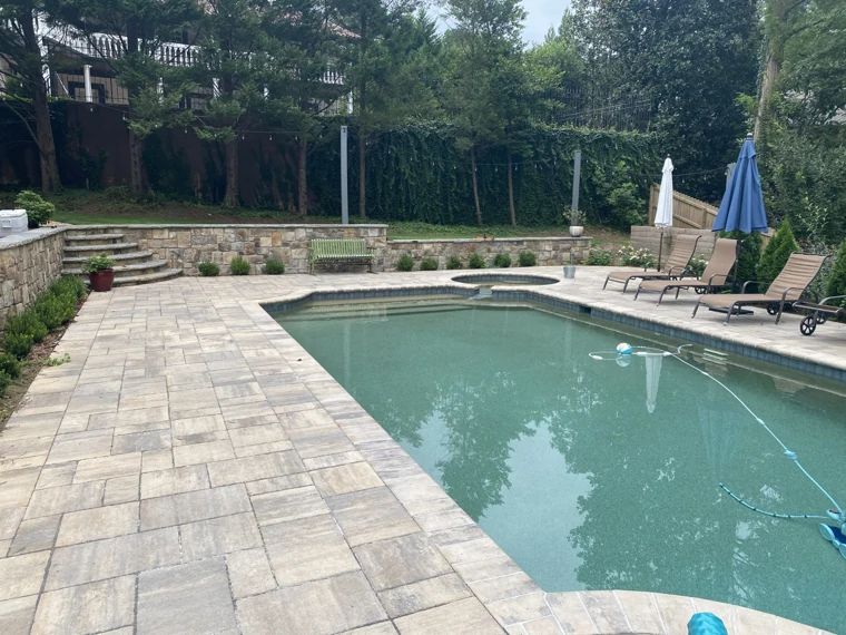 Swimming pool with a broad stone pool deck and lounge chairs