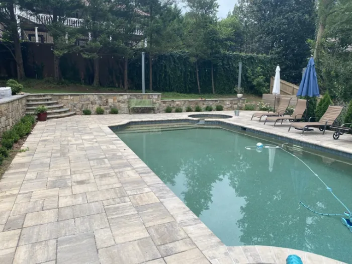 Swimming pool with a broad stone pool deck and lounge chairs