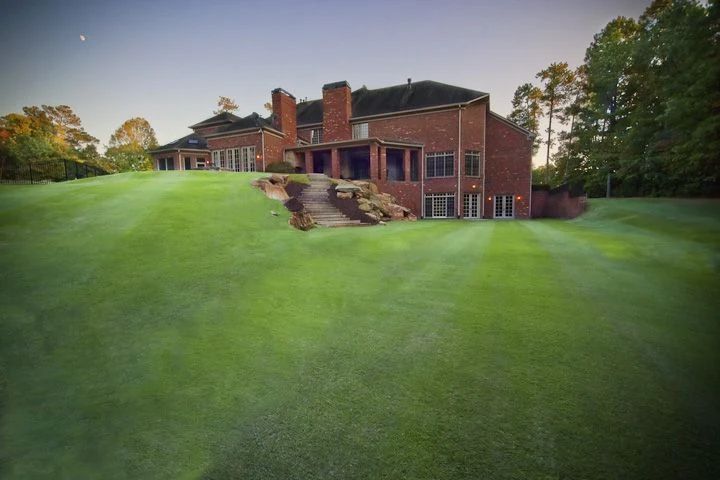 Broad lawn and terraced stone steps behind a brick home