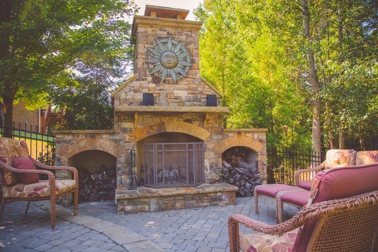 Outdoor stone fireplace surrounded by colorful seating and mature trees