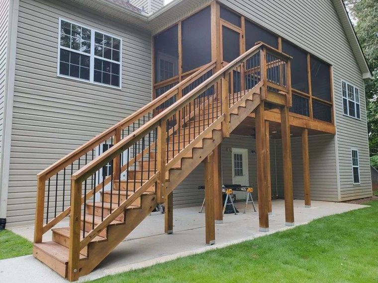 Raised wood deck with broad stairs and dark metal balusters