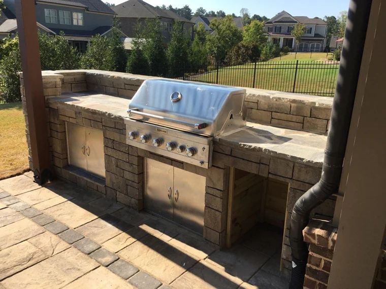 Stainless steel built-in grill in a stone outdoor kitchen