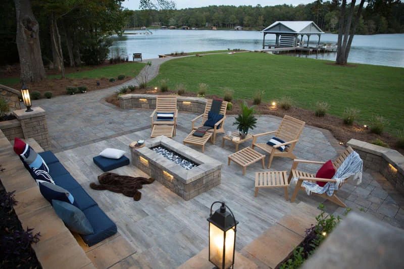 Lakeside patio with wood lounge chairs and a square fire pit