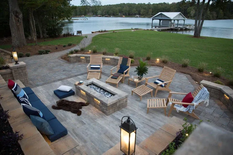 Lakeside patio with wood lounge chairs and a square fire pit