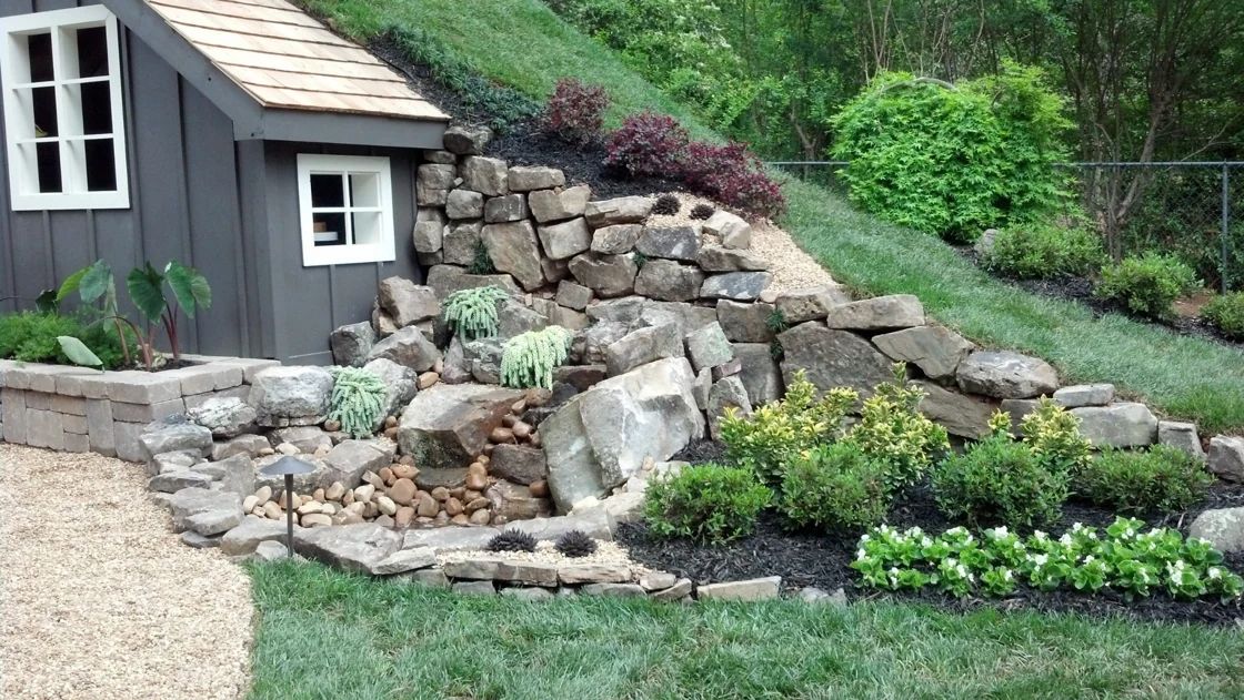 Boulder waterfall and planted garden beside a house