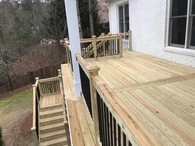 Raised wood deck and stairs overlooking a wooded yard