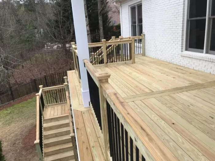 Raised wood deck and stairs overlooking a wooded yard