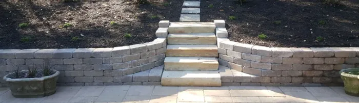 Curved retaining wall and broad stone steps adjoining a patio