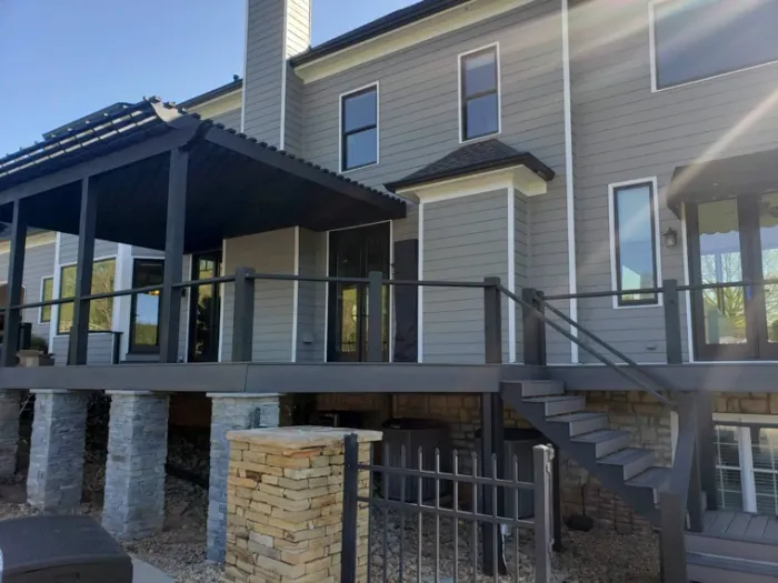 Raised composite deck and pergola with black rails and stone columns