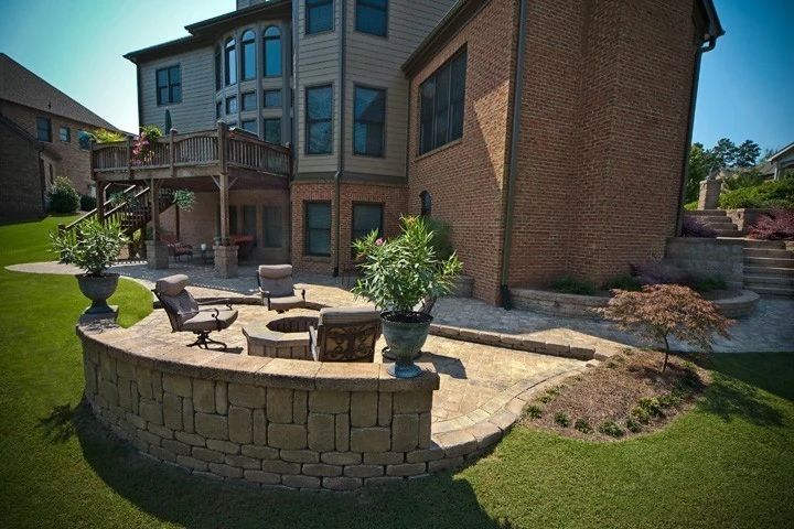 Raised paver patio with a curved stone wall and fire pit seating