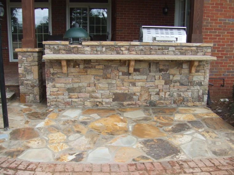 Stone outdoor kitchen bar with stainless grill and kamado cooker