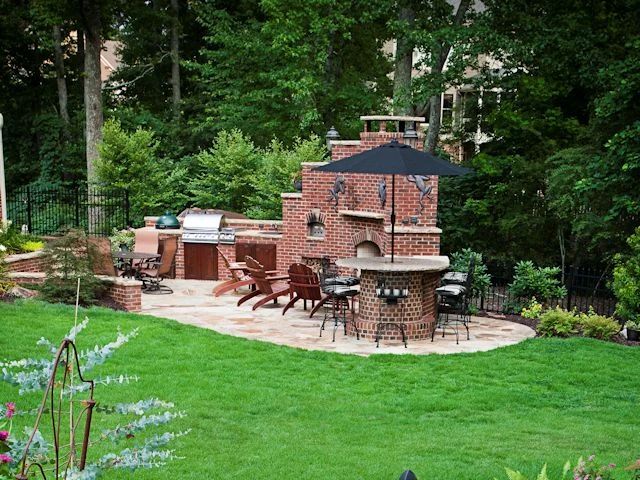 Brick outdoor kitchen and pizza oven across a landscaped lawn