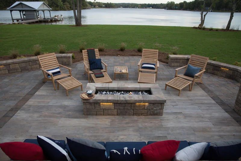 Lakeside patio with wood lounge chairs around a square fire pit