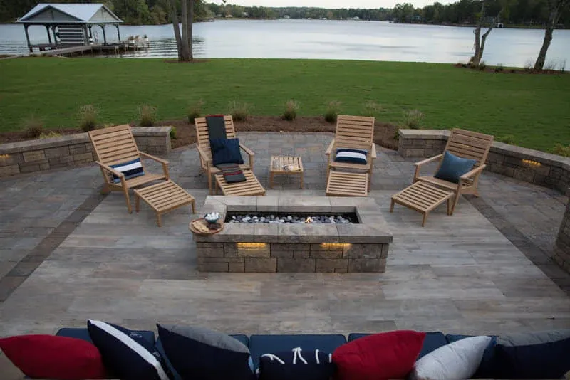 Lakeside patio with wood lounge chairs around a square fire pit
