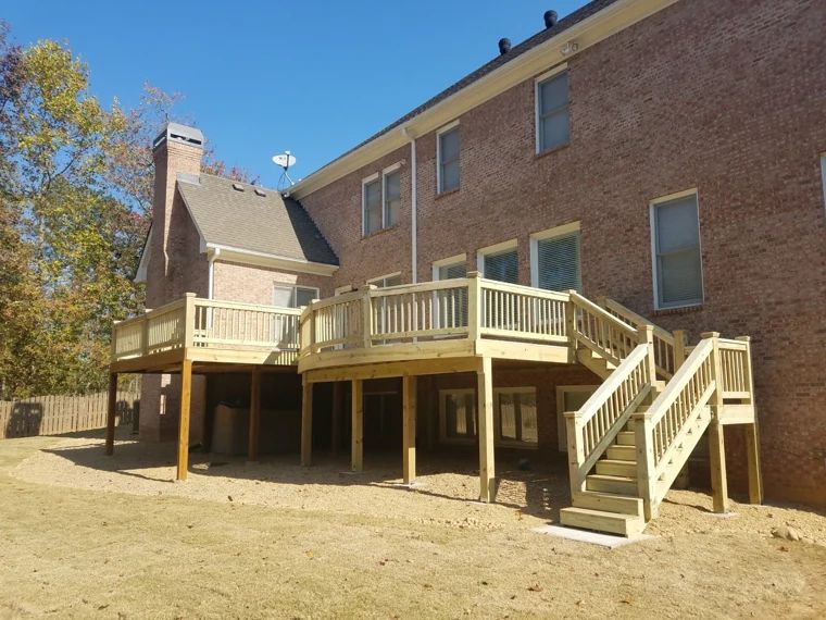 Multi-level wood deck and stairs at the back of a brick home