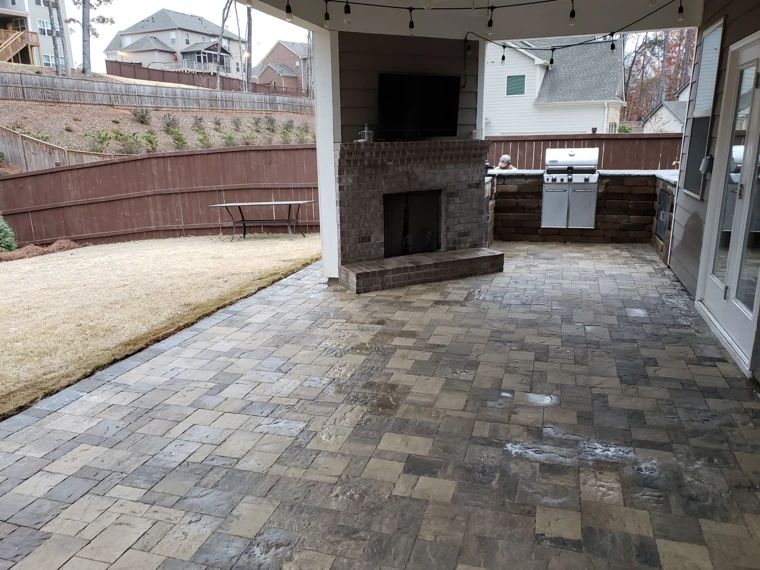 Covered paver patio with a stone fireplace and built-in outdoor grill