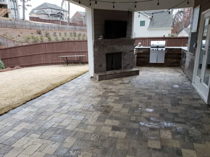 Covered paver patio with a stone fireplace and built-in outdoor grill