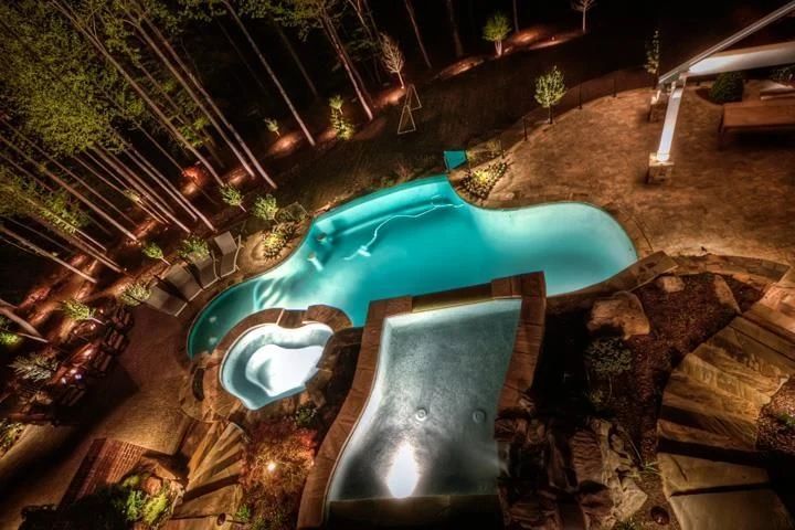Illuminated swimming pool and raised spa at night