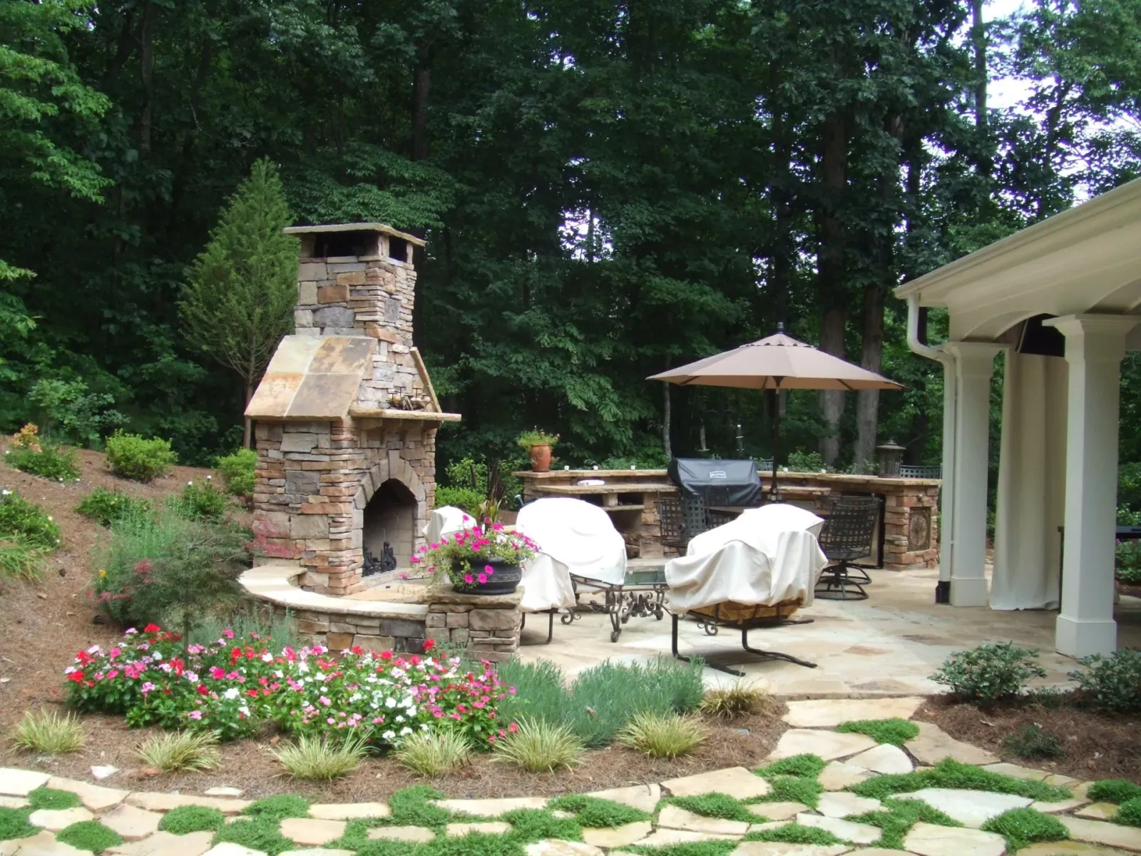Garden path and flower beds leading to an outdoor fireplace and patio