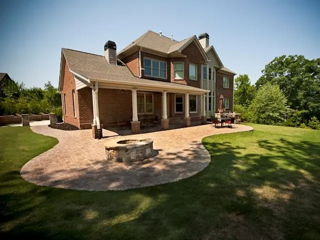 Paver patio and fire pit connecting a covered porch to the lawn