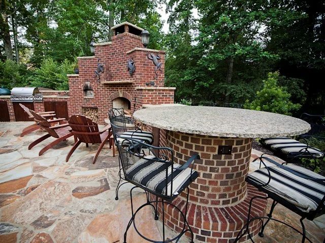 Brick outdoor kitchen with pizza oven, stone counter, and bar seating
