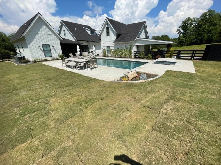 Backyard swimming pool and outdoor dining area beside a modern farmhouse