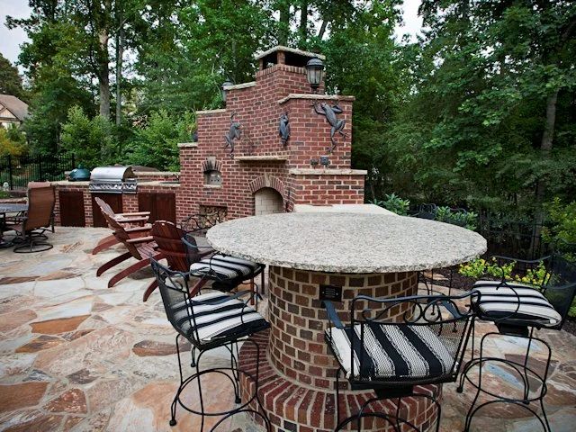Brick pizza oven and outdoor kitchen with stone paving and bar seating