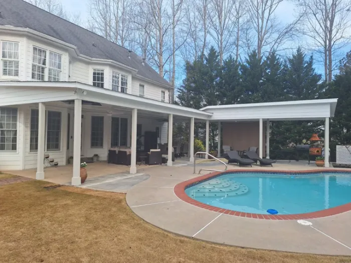Swimming pool and paved pool deck beside a covered outdoor living space