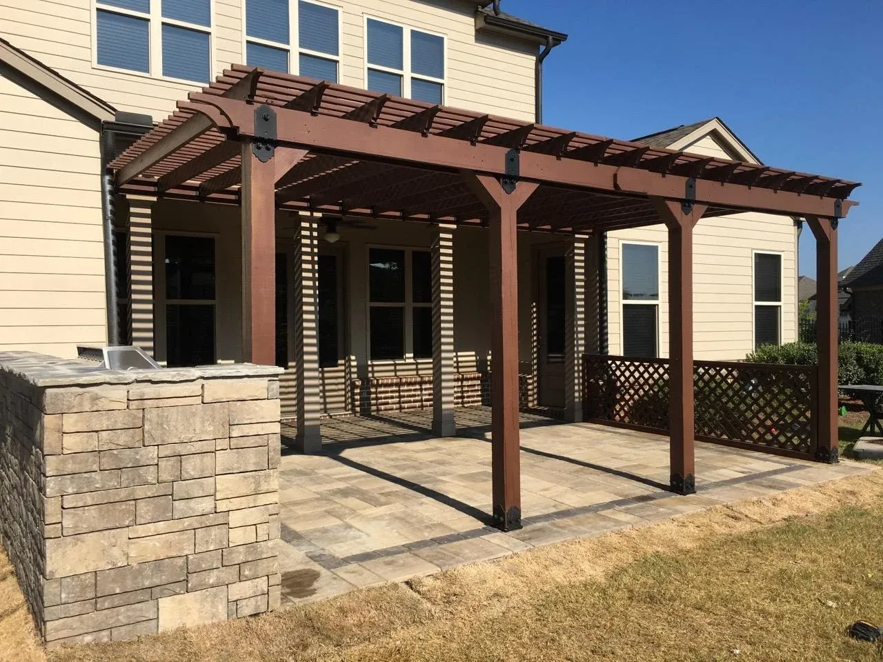 Timber pergola and stone outdoor kitchen on a paver patio