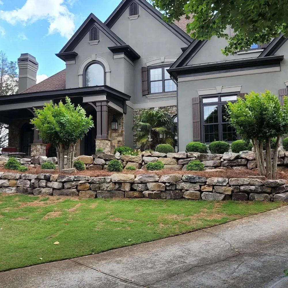 Boulder retaining walls and ornamental trees framing a landscaped home